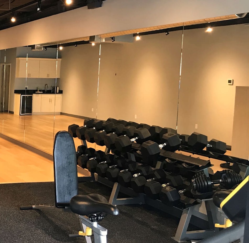 The private training studio at 2228 Eastlake Ave E in Seattle: maple floor, mirrored wall, dumbbell rack and adjustable bench
